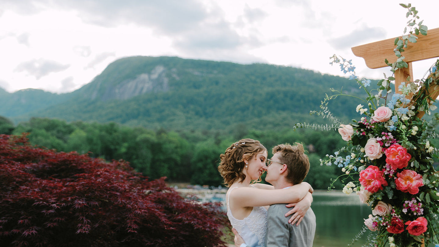 Two people getting married next to wedding flowers on an arch at Rumbling Bald