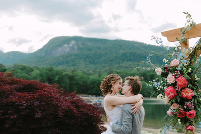 Two people getting married next to wedding flowers on an arch at Rumbling Bald